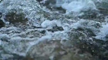 mountain river flowing through stone rapids in the Carpathians in slow motion, water flow in slow motion, rushing water and bubbles.