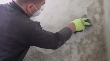 Evde mantar ve küf temizleme, duvardaki ilk mantar katmanını bir spatulayla soyma, yavaş çekim video.