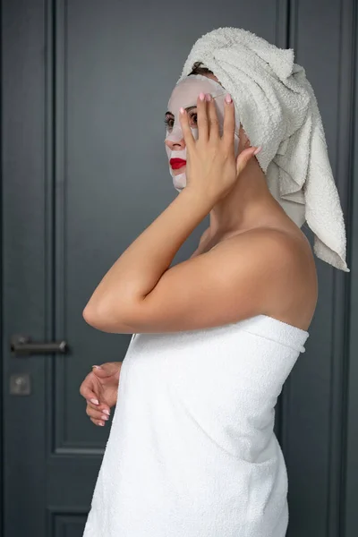 Home facial care, cloth mask on girl\'s face, girl wrapped in a towel.