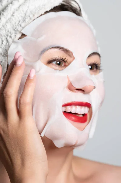 Fabric refreshing face mask, skin care, portrait of a woman with a mask on her face.