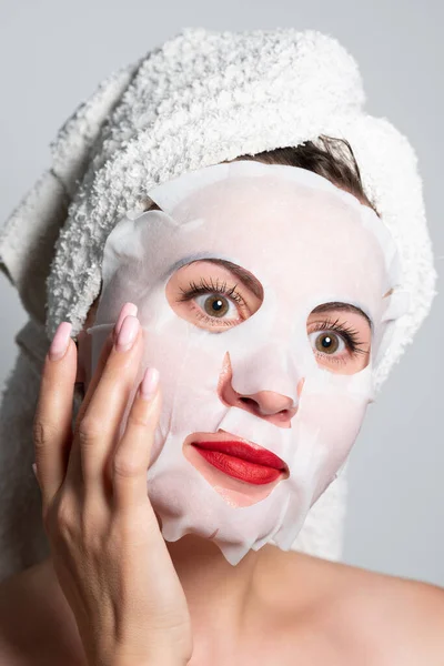 Fabric refreshing face mask, skin care, portrait of a woman with a mask on her face.