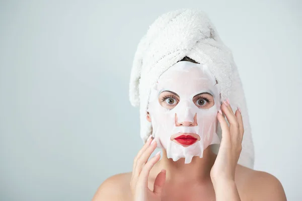 Portrait of a woman with a cotton mask to moisturize her face, place for advertising and inscription.