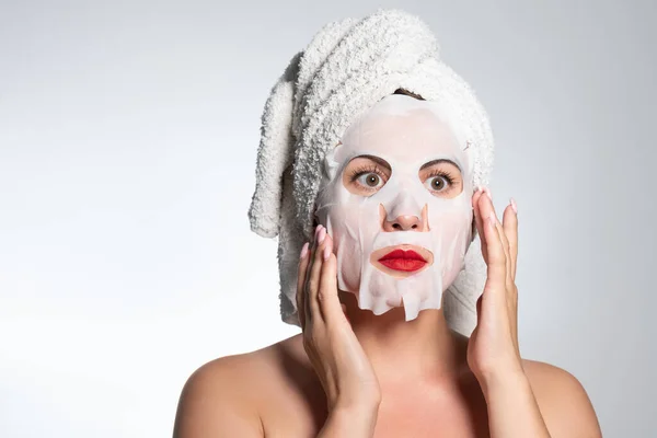 Portrait of a woman with a cotton mask to moisturize her face, place for advertising and inscription.