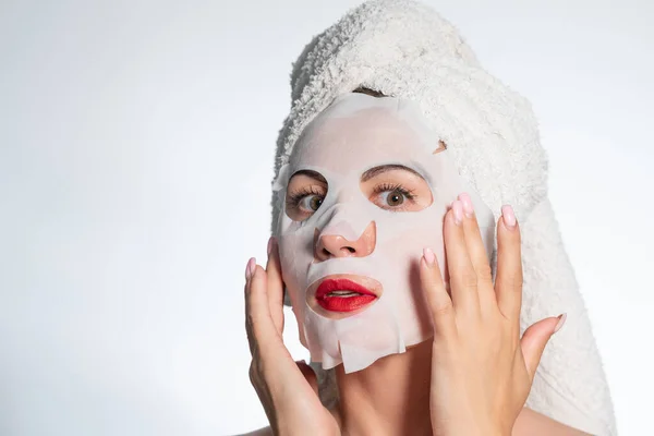 Woman with a towel on her hair and a mask on her face, skin and hair care, place for advertising and inscription.