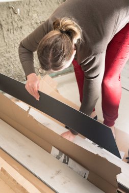 Kadın kutudan bir kuvars plağı çıkarır, zemini onarmak için tamir eder..