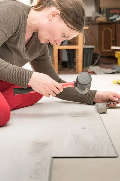 Woman installs quartz vinyl floor, installation on a flat surface quartz vinyl floor, repair work in the house.