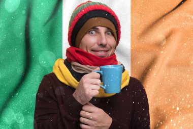 Ireland and the gas winter crisis, high gas tariffs for the public, a smiling man warms himself with a cup of tea and warm clothes.