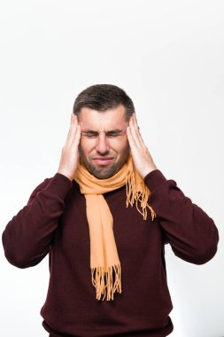 A man holds his hand on his head because of a headache, a portrait of a man on a white background, a man's neck is wrapped in a scarf.