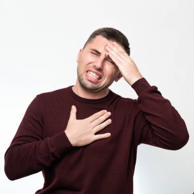 Emotions of a man from a headache, a man suffers from a severe migraine, portrait on a white background isolated.