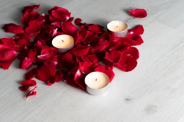 Rose petals and scented candles on the floor, unlit candles between the petals.