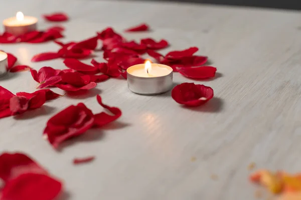 Scattered rose petals and candles, aromatic rose fragrance and candle aroma, spa relaxation.