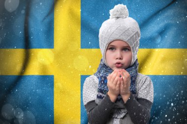 Cold winter and the consequences of gas sanctions, the consequences of the war in Ukraine, the shortage of gas and heat in Sweden, a little girl is frozen, a child without heat in winter blows his hands to keep warm.