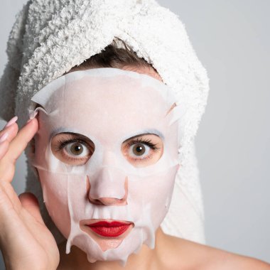 Fabric refreshing face mask, skin care, portrait of a woman with a mask on her face.