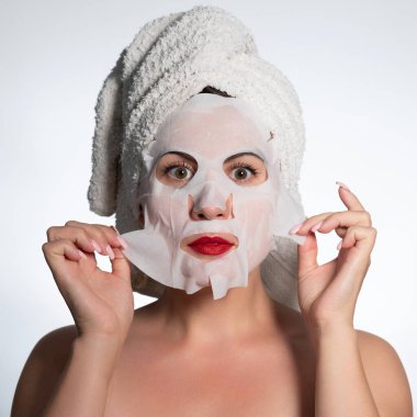 Portrait of a woman with a cotton mask to moisturize her face, place for advertising and inscription.