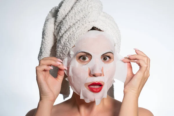 Woman with a towel on her hair and a mask on her face, skin and hair care, place for advertising and inscription.