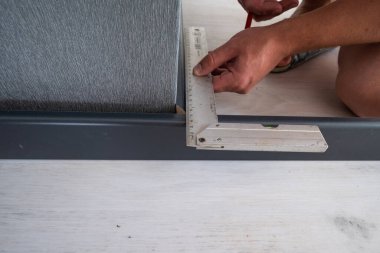 Installing a plinth in the room, measuring the required length using a square and a ruler, notching the plinth at the corner.
