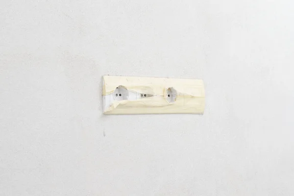 White sockets on a white wall, a socket for a TV antenna, sockets with masking tape.