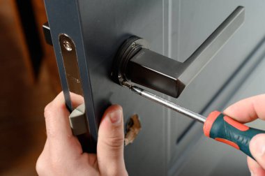 Ivano-Frankivsk, Ukraine May 16, 2022: installation of the door lock, screwing the handle to the lock.