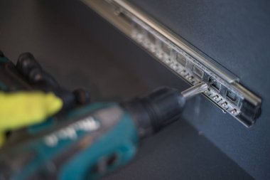 Bir durumda sürgülü mekanizmanın vidalanması, bir çekmece için sürgülü mekanizma, gri renkli bir kayan gardırop.