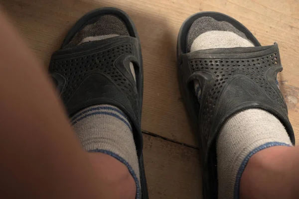 Human feet in socks and slippers, torn slippers on a human foot, children\'s feet.