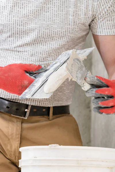 Lime plaster on a spatula, repair and decoration work with lime plaster, two dirty spatulas, lime plaster in a bucket.