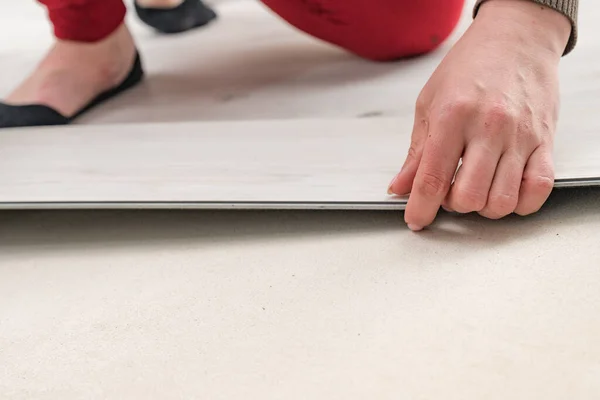 Floor installation, a new style of quartz vinyl floor, repair work to install the floor, a woman installs the floor.