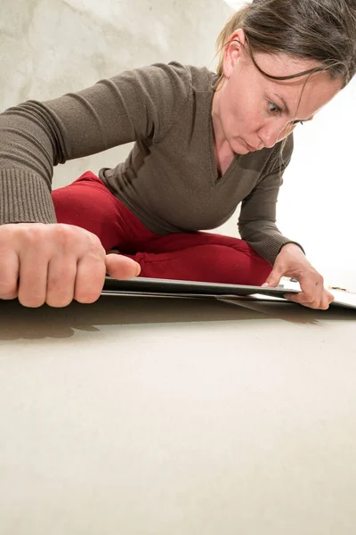 Woman installs quartz vinyl flooring at home, exhausted woman from work, installation of quartz vinyl flooring.