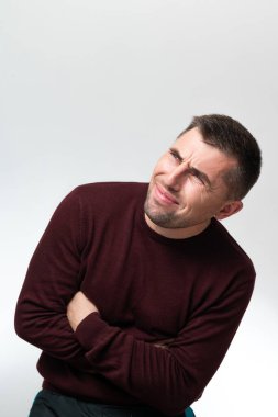 A man touches his stomach with two hands, on a white background with copy space, Stomach pain in a man, unbearable abdominal pain.