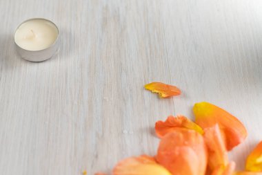 Rose petals and scented candles on the floor, unlit candles between the petals.