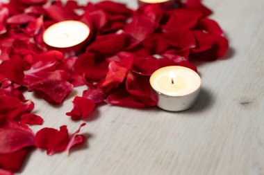Scattered rose petals and candles, aromatic rose fragrance and candle aroma, spa relaxation.