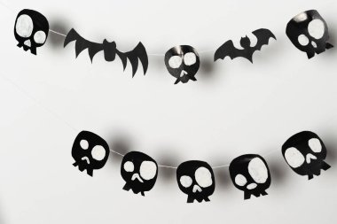 Bats and skulls black on a white background, place to write a greeting, paper craft for Halloween.