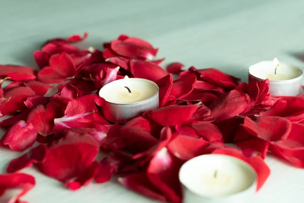 Scattered rose petals and candles, aromatic rose fragrance and candle aroma, spa relaxation.
