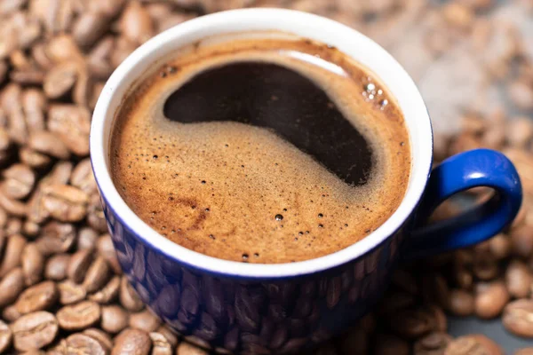 近くに豆が散乱したコーヒーカップ ホットコーヒーからの軽い蒸気 — ストック写真