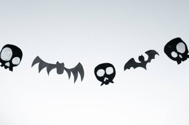 Bats and skulls black on a white background, place to write a greeting, paper craft for Halloween.