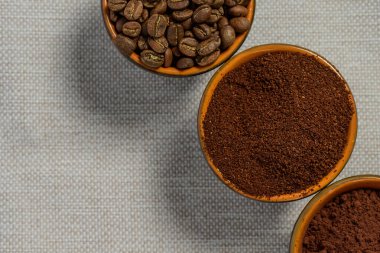 Kahve çekirdekleri, keten arka planda fincanda öğütülmüş kahve bağımlılığa neden olan aromatik bir içecek..