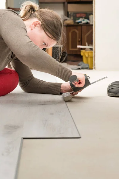 Woman installs quartz vinyl floor, installation on a flat surface quartz vinyl floor, repair work in the house.