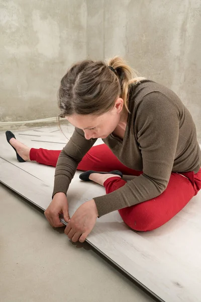 Woman installs quartz vinyl flooring at home, exhausted woman from work, installation of quartz vinyl flooring.