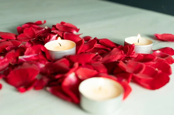 Scattered rose petals and candles, aromatic rose fragrance and candle aroma, spa relaxation.