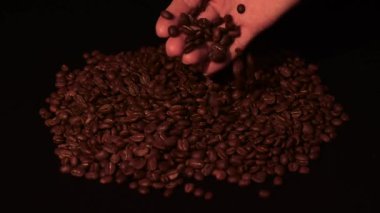 Adam kahve çekirdeklerini eliyle dolduruyor, yavaş çekim ve siyah arkaplan, HD video ve kopyalama alanı.