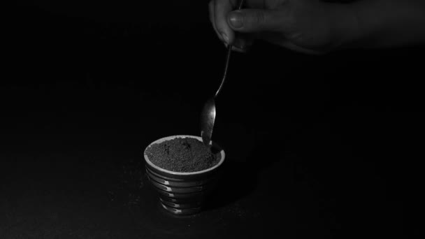 地面のコーヒーはスローモーションでカップにスプーンから落ちる カップは黒の背景にグランドコーヒー スローモーションHdとビデオで満たされています — ストック動画