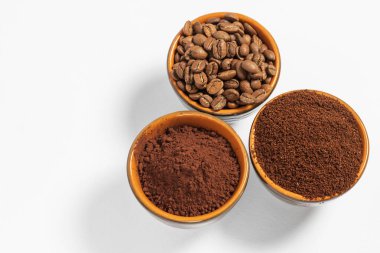 Kavrulmuş kahve çekirdekleri, öğütülmüş kahve fincanları, beyaz arka plan ve fotokopi alanı, arka plandaki fincanların gölgesi..