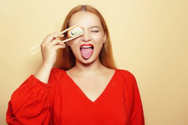 Beyaz bir tabakta suşi yiyen güzel bir kız. Kırmızı elbiseli ve kırmızı dudaklı bir kadın Philadelphia somonuyla suşi yiyor. Manken yüzünü buruşturur ve gözlerini yuvarlarken eğlenir..