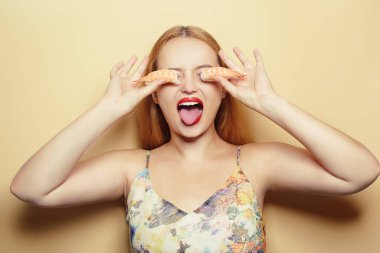 Güzel sarışın gözlerini karidesle kapatıyor. Mesaj için yer, rulo ile poz veren bir model. Japon mutfağı restoranı. Turuncu arka planda gülümseyen ve dil gösteren bir kadın.