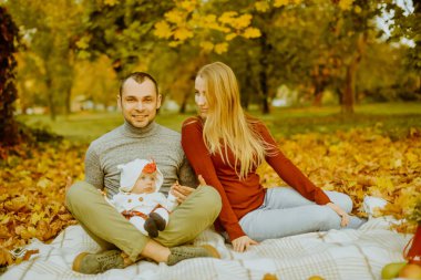 Sonbaharda düşen yaprakların üzerinde oturan çift, güzel bir sonbahar gününün tadını çıkarıyorlar. Mutlu, genç aile babası, anne ve küçük kız dışarıda eğleniyor.. 