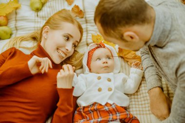 Birbirine aşık çift, sonbahar yaprakları üzerinde parka uzanmış, halının üzerine uzanmış, güzel bir sonbahar gününün tadını çıkarıyorlar. Mutlu, genç aile babası, anne ve küçük kız dışarıda eğleniyor.