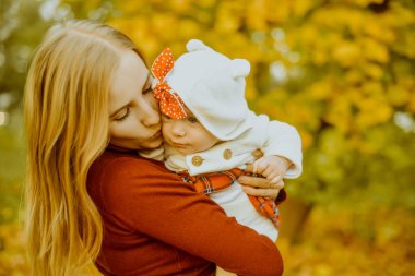 Mutlu, genç bir aile annesi ve küçük bir kız çocuğu dışarıda eğleniyorlar. Ebeveynler uçan bebeklerini öperler. Anne ve kızı sonbaharda bir parkta yaprakları dökülüyor, güzel bir sonbahar gününün tadını çıkarıyorlar.. 