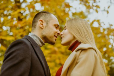 Kız ve erkek ya da sevgili kucaklaşması. Parkta aşık bir çift. Sonbahar. Erkek ve kadın, sonbaharda düşen yapraklarla gülerek güzel bir sonbahar gününün tadını çıkarırlar. Sonbaharda genç bir çift. Öptüm.