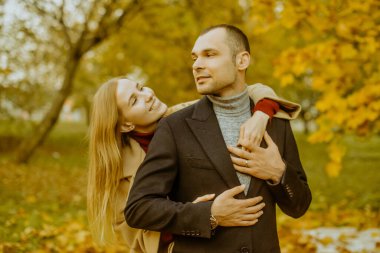 Kız ve erkek ya da sevgili kucaklaşması. Parkta aşık bir çift. Sonbahar. Erkek ve kadın, sonbaharda düşen yapraklarla gülerek güzel bir sonbahar gününün tadını çıkarırlar. Sonbaharda genç bir çift.