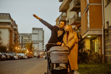 Bir çift, akşam evlerin yakınındaki bir çocuk için bebek arabasıyla yürüyüşe çıkıyor. Çocuklar ve temiz hava. Aile, karı koca Sonbaharda sokaklarda