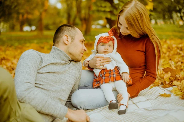 Sonbaharda düşen yaprakların üzerinde oturan çift, güzel bir sonbahar gününün tadını çıkarıyorlar. Mutlu, genç aile babası, anne ve küçük kız dışarıda eğleniyor.. 